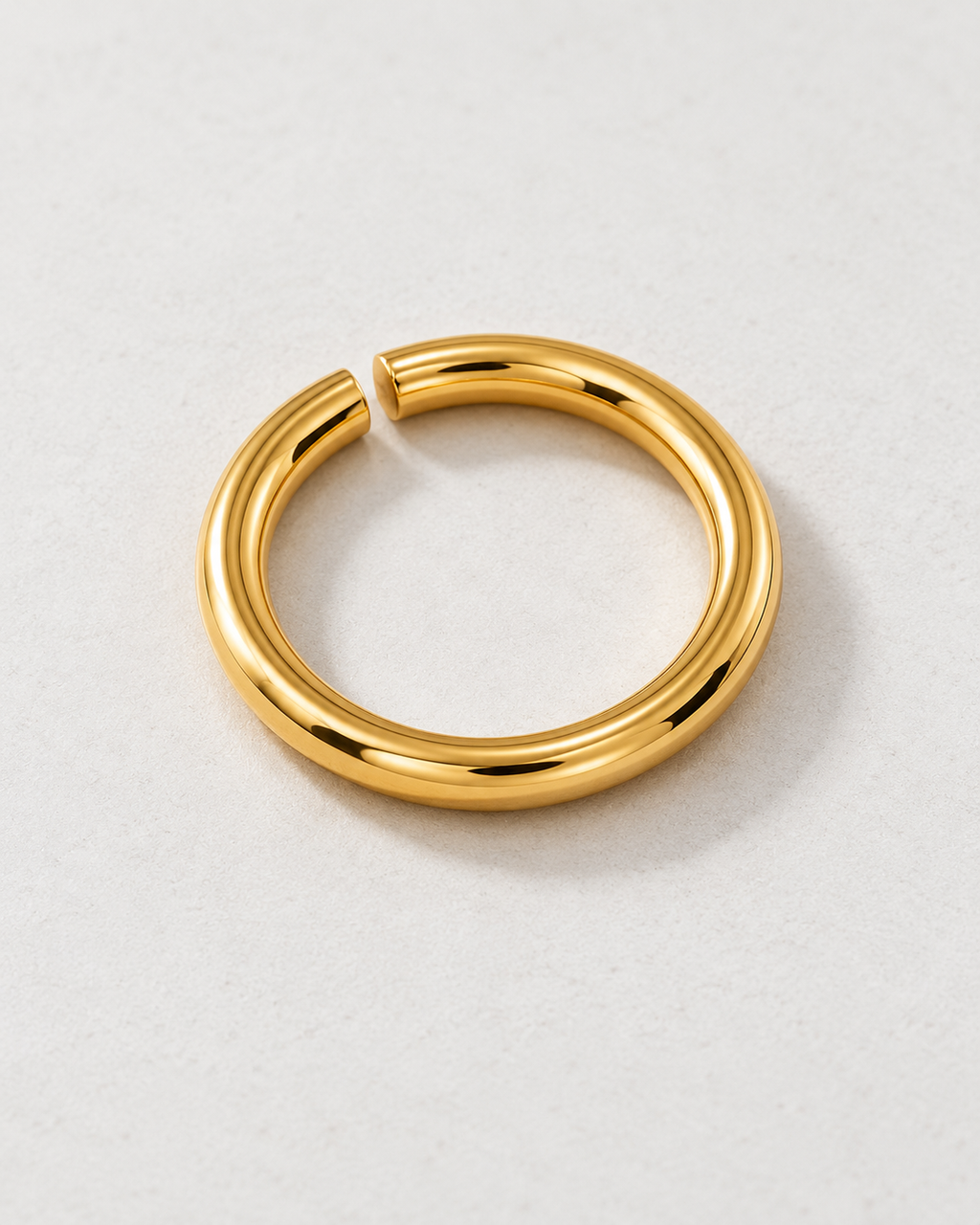 Offset Ring — Gold tone — rounded open band on pale concrete