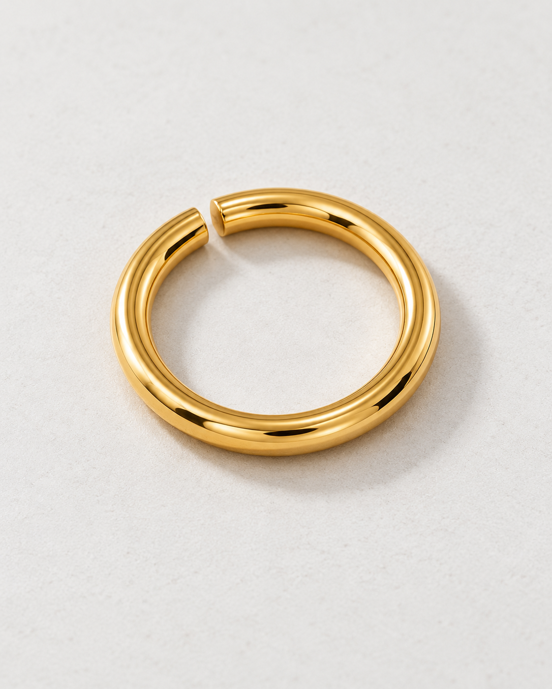 Offset Ring — Gold tone — rounded open band on pale concrete