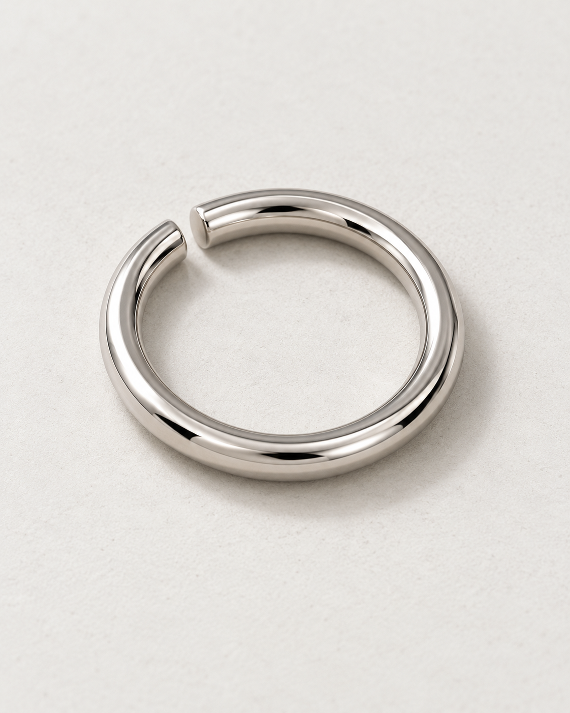 Offset Ring — Polished steel — rounded open band on pale concrete