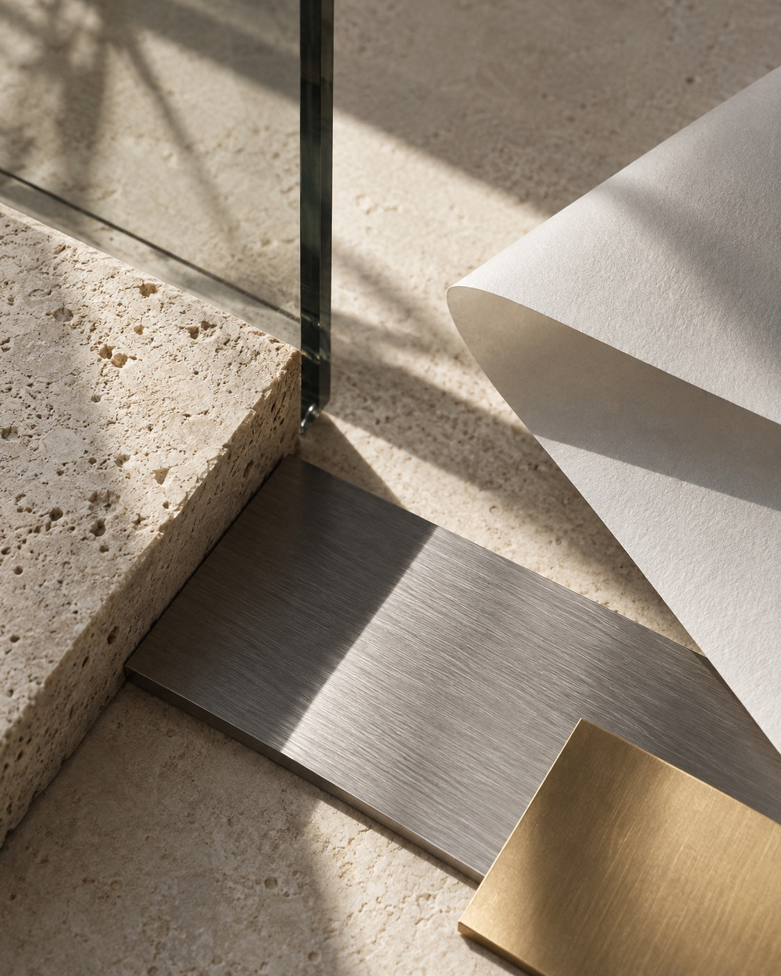 Limestone, brushed steel, paper, glass, and champagne-colored metal in daylight